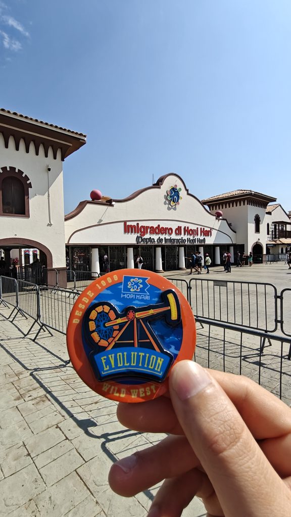 Ímã personalizado da atração Evolution Wild West segurado em frente à entrada do Hopi Hari, souvenir fabricado pela Arteria Brasil